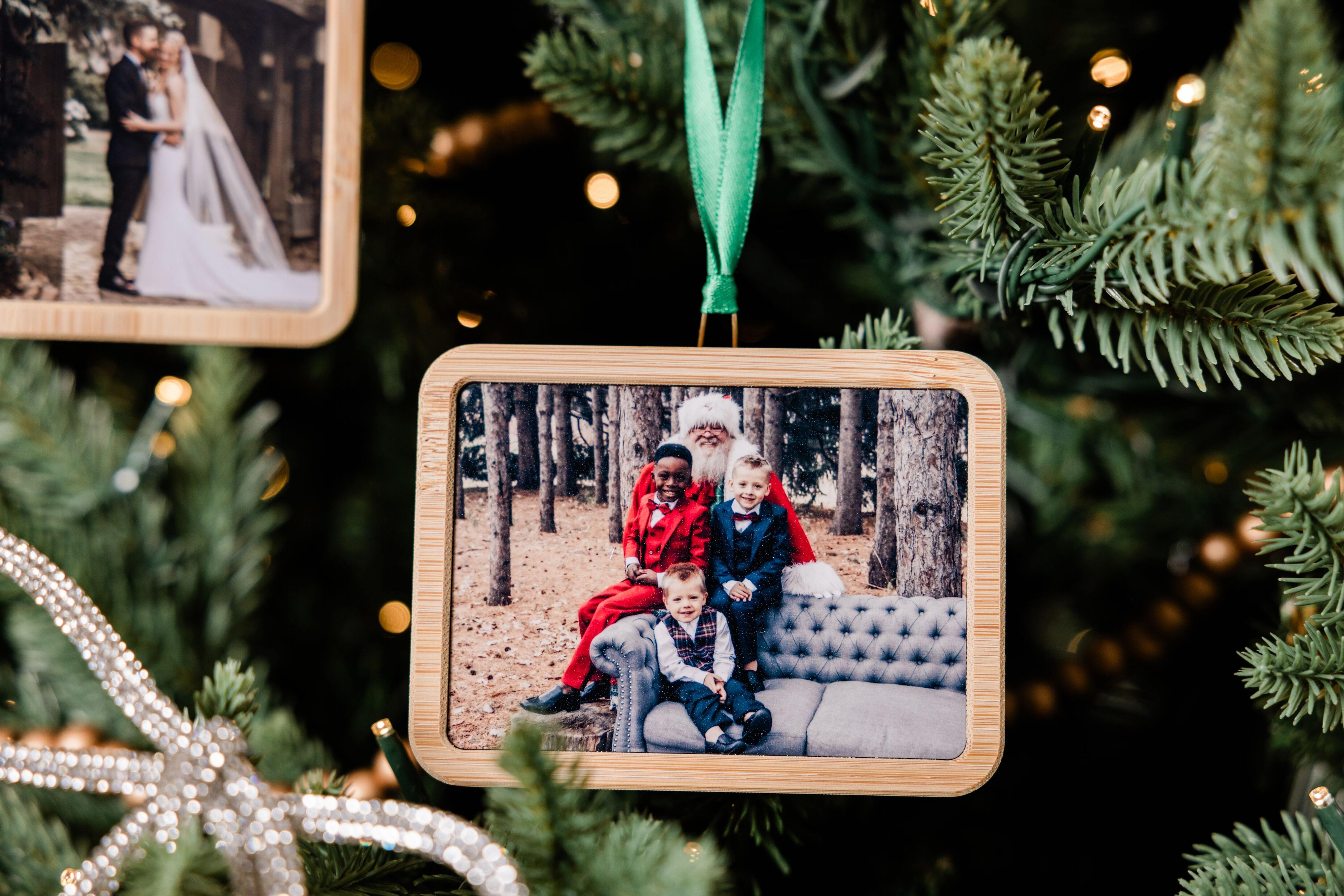 Horizontal rectangle bamboo Framed Ornament hanging on a Christmas tree with a family photo featuring Santa