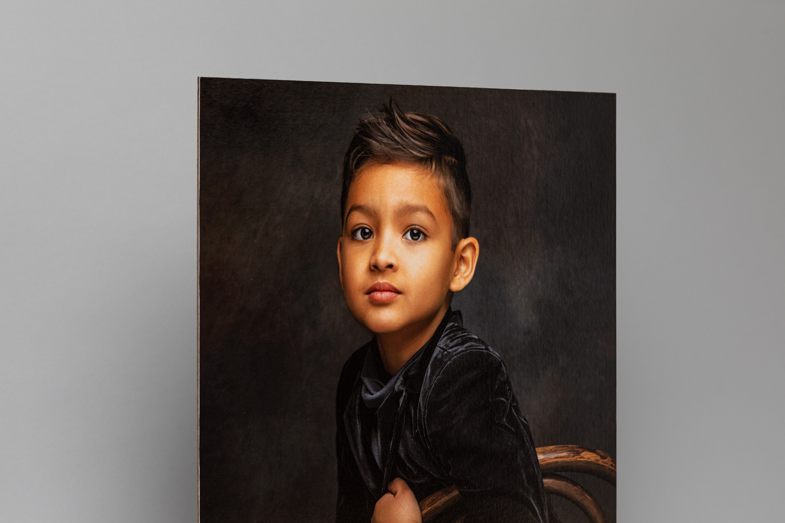 Boy seated for a formal, professional studio portrait printed on Portrait Canvas mounted on Masonite, gray background