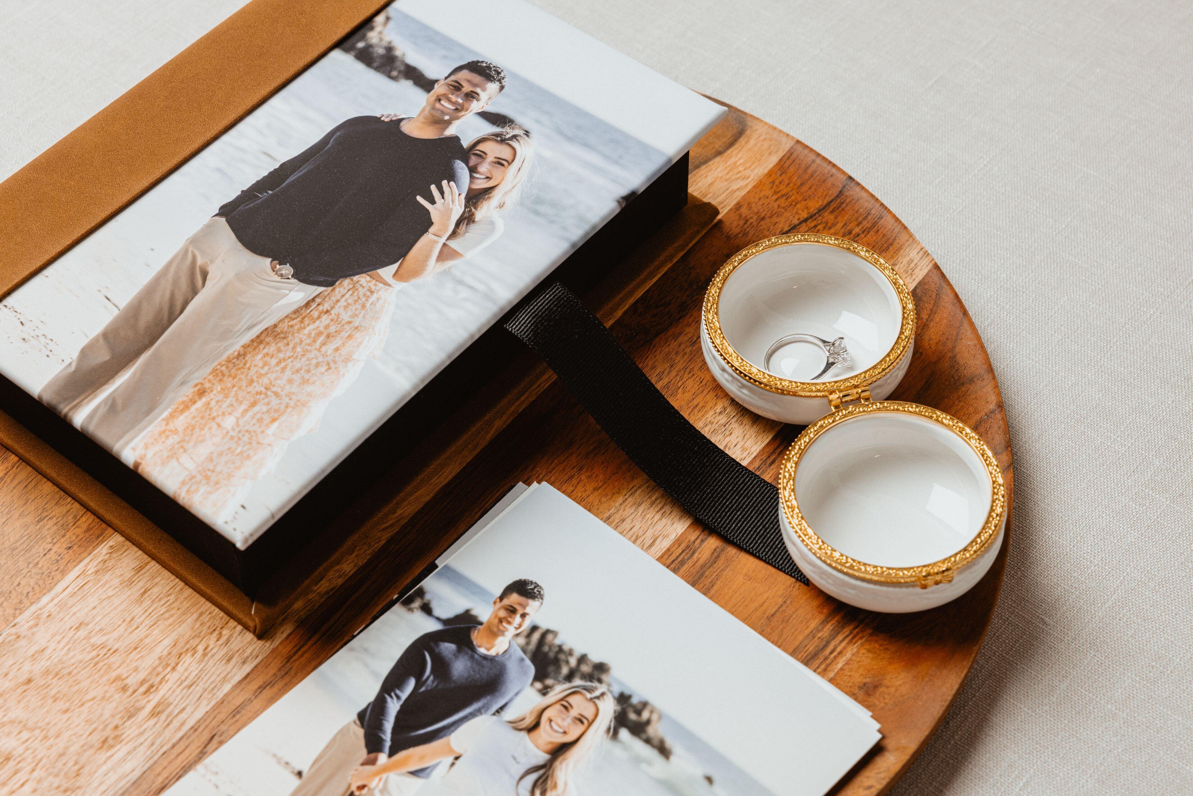 Print Box with a photo cover beside loose prints of a couple on a wood tray