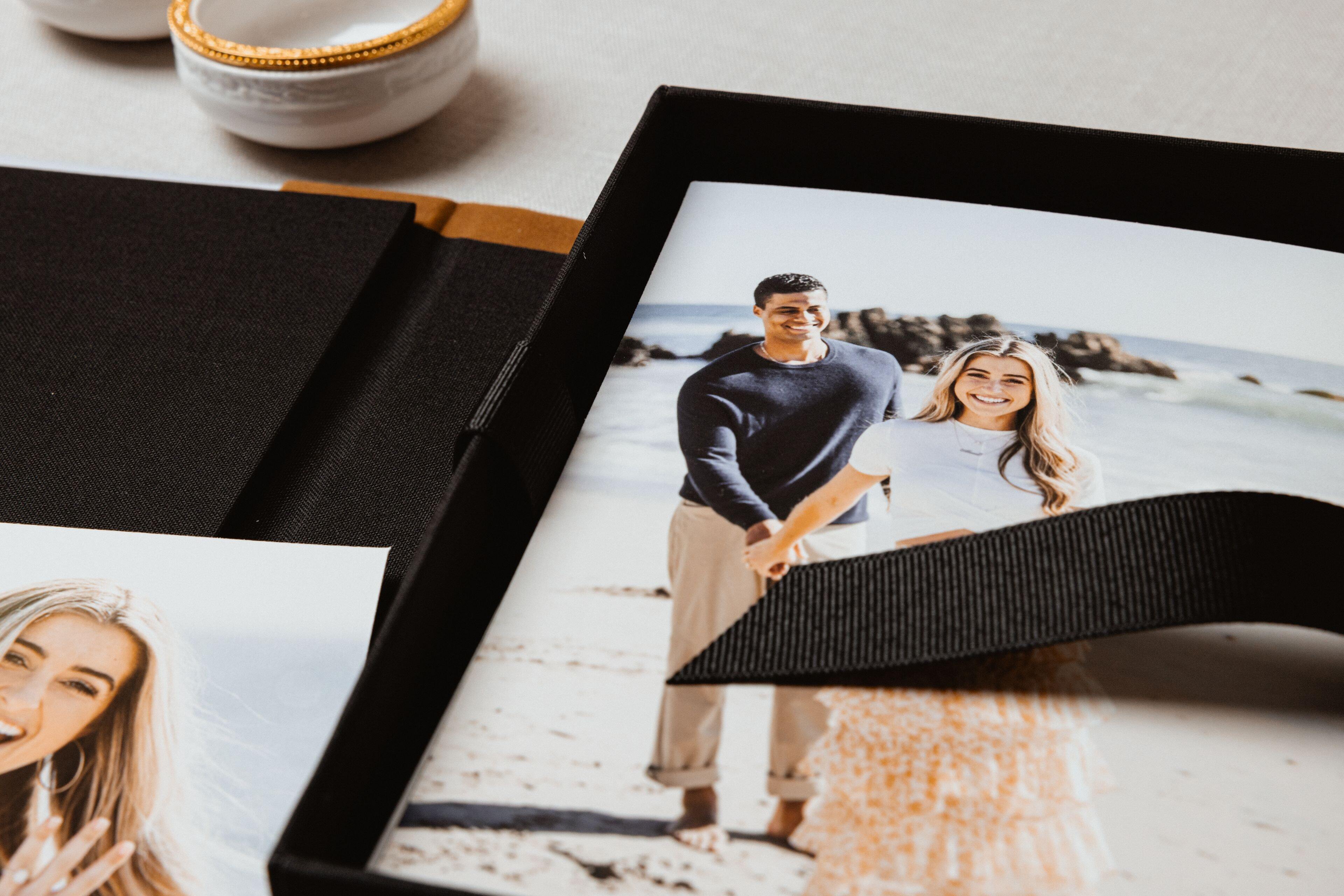 Open Print Box with a black ribbon pull holding prints of a couple on the beach