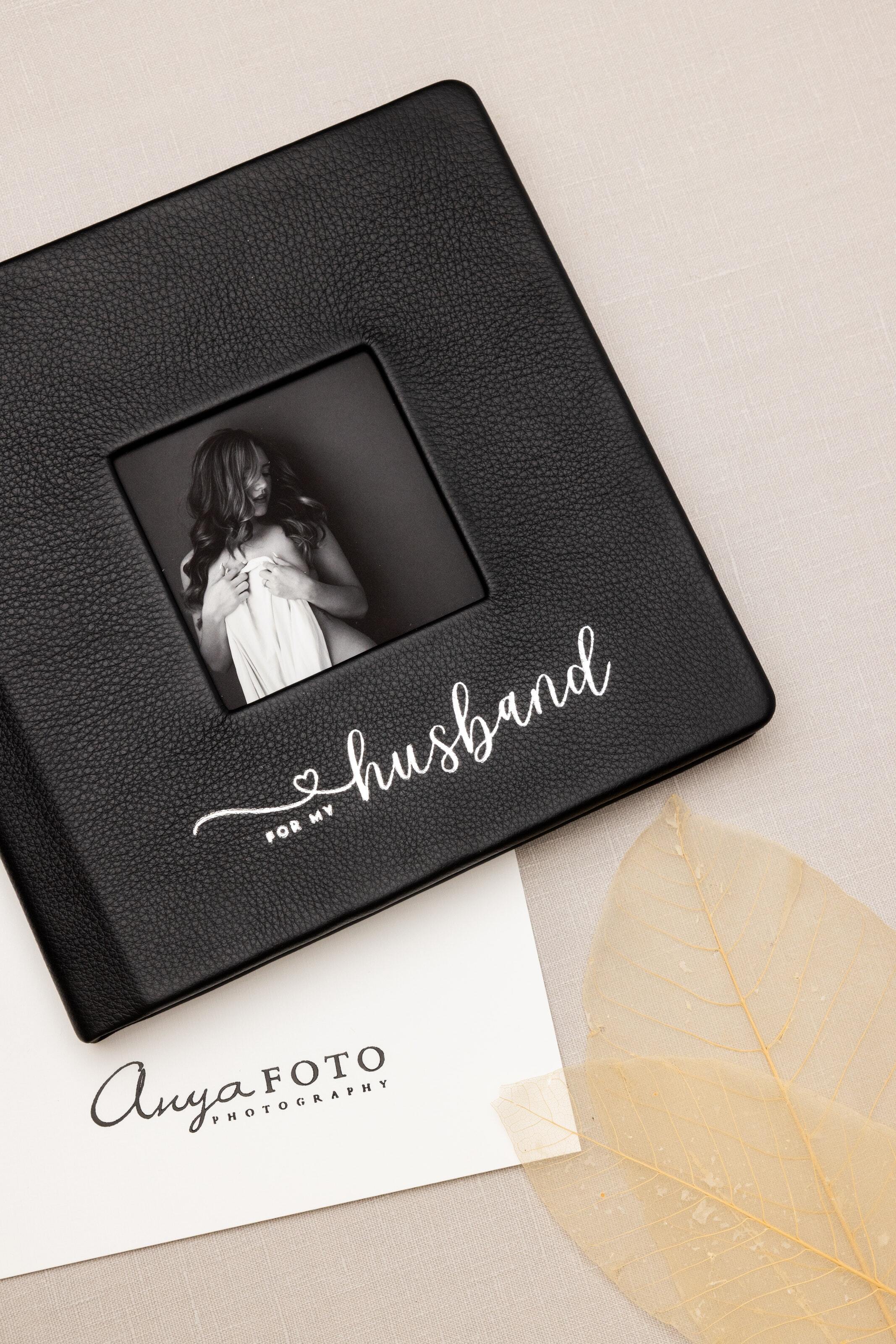 Black Premier Leather Album with cameo opening and white foil custom debossing reading "for my husband". This is laying flat on a table and also shows custom debossed endleafs.