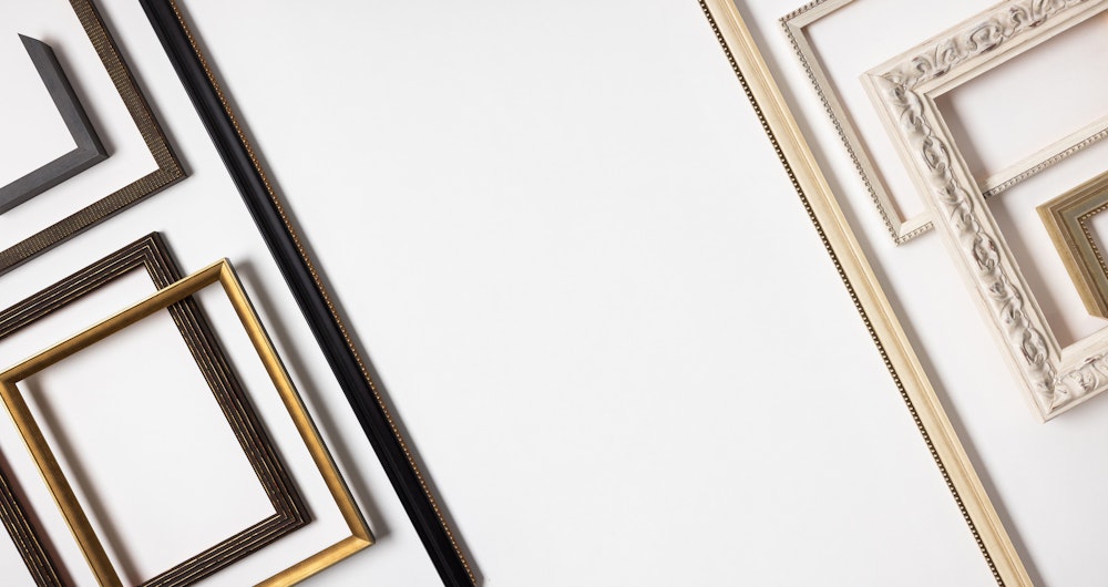 Flatlay of various black, dark brown, gold, ivory, and white Framed Print mouldings arranged into a pattern from dark to light