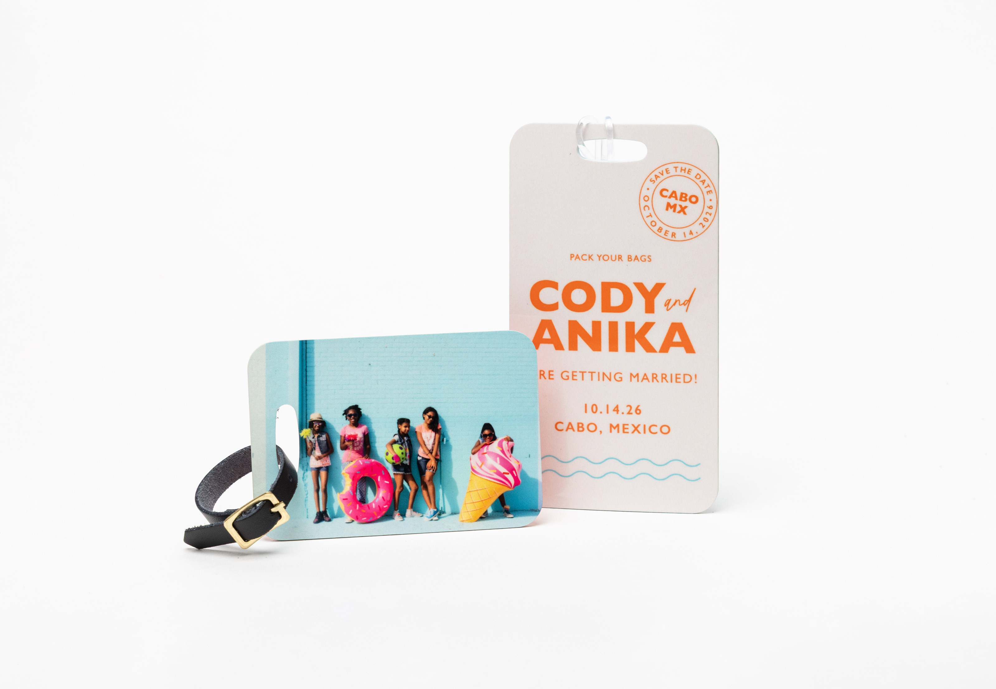 Colorful children's portrait printed on a small Bag Tag with a black leather strap, and a destination wedding design on a large Bag Tag with a clear plastic strap, standing on a white background.