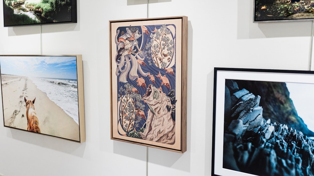 Digital illustration of an archer and bear in an imaginative style, printed on a Wood Print so the grain texture shows through, and displayed in a Walnut Wood Float Frame. Hanging on a white gallery wall with other framed nature photography prints.