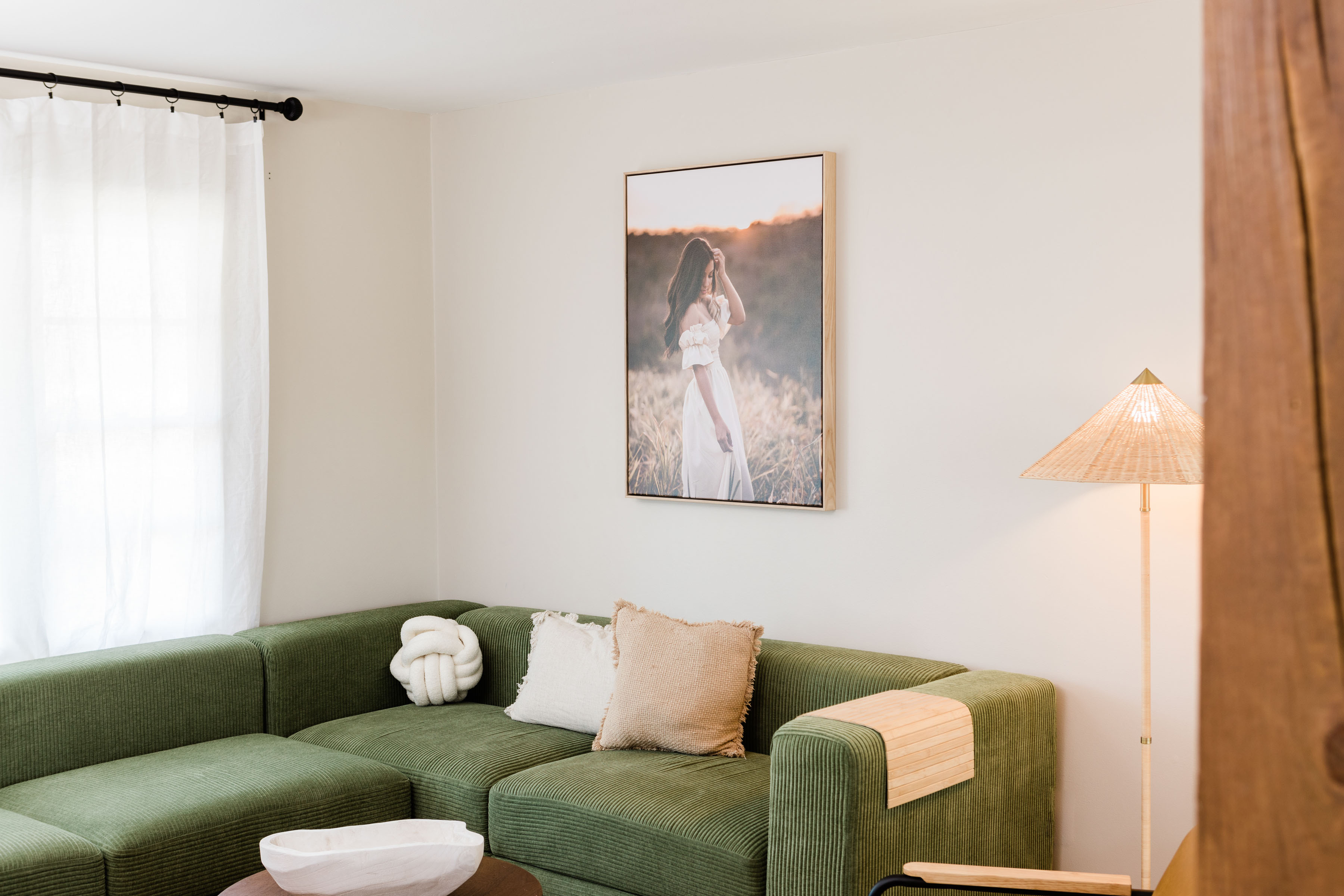 Portrait in a sold wood float frame hung above a green couch.