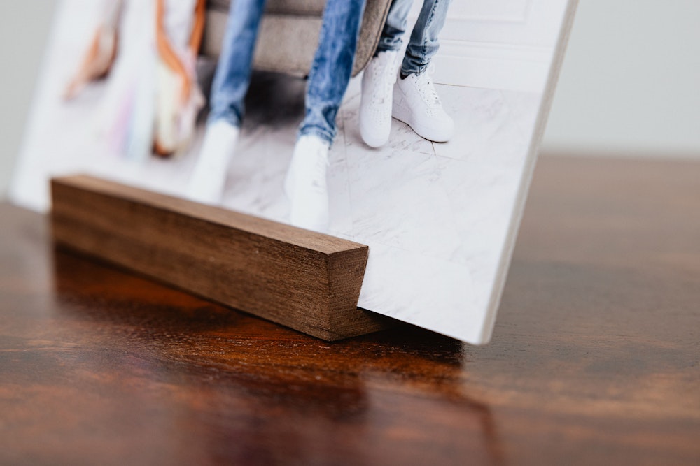 Walnut wood display stand corner detail with mounted family portrait print on a table