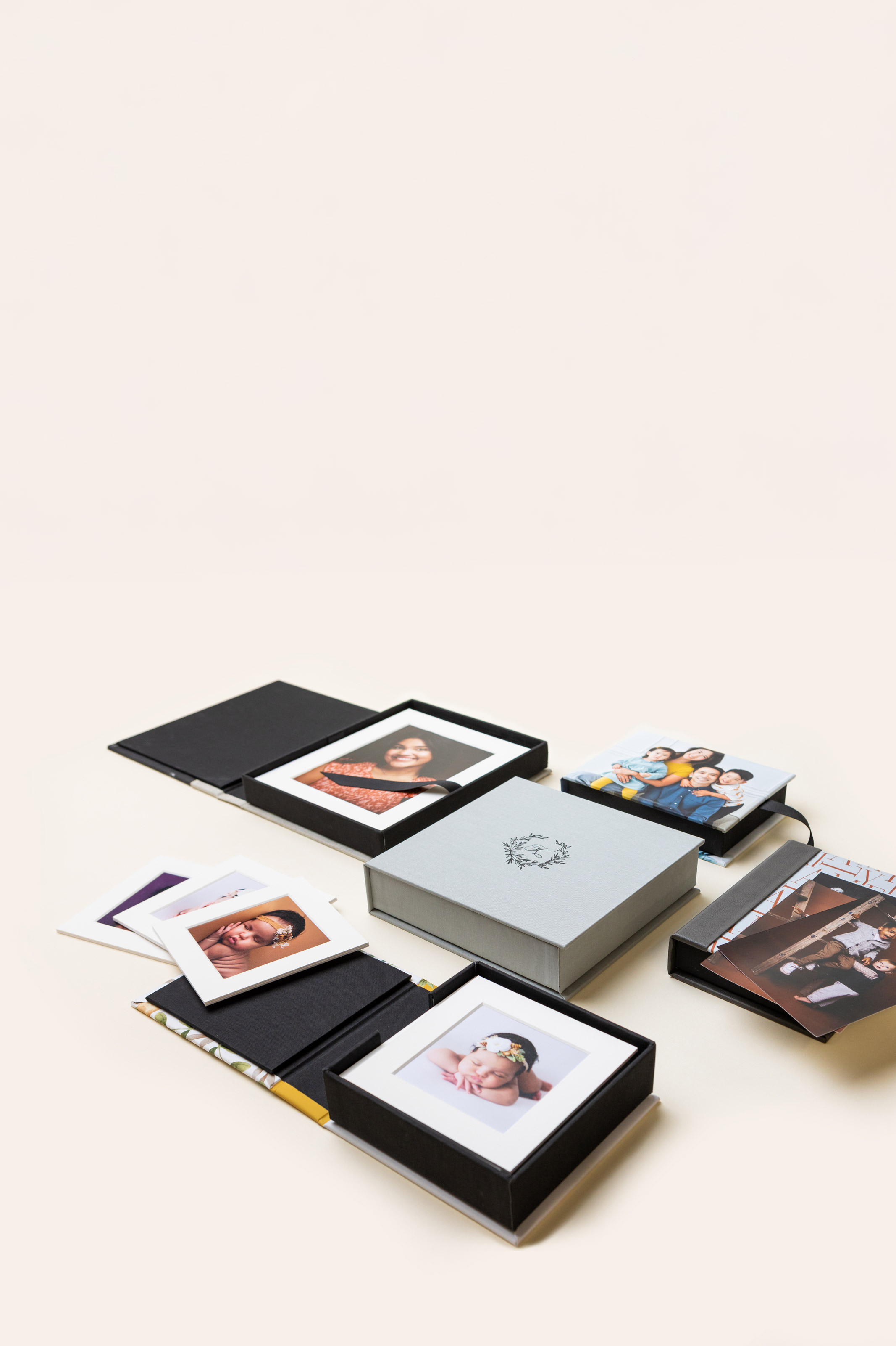 Several 3-Panel Print Boxes arranged on cream background, featuring debossed material and photo covers featuring imagery from various portrait photography sessions.