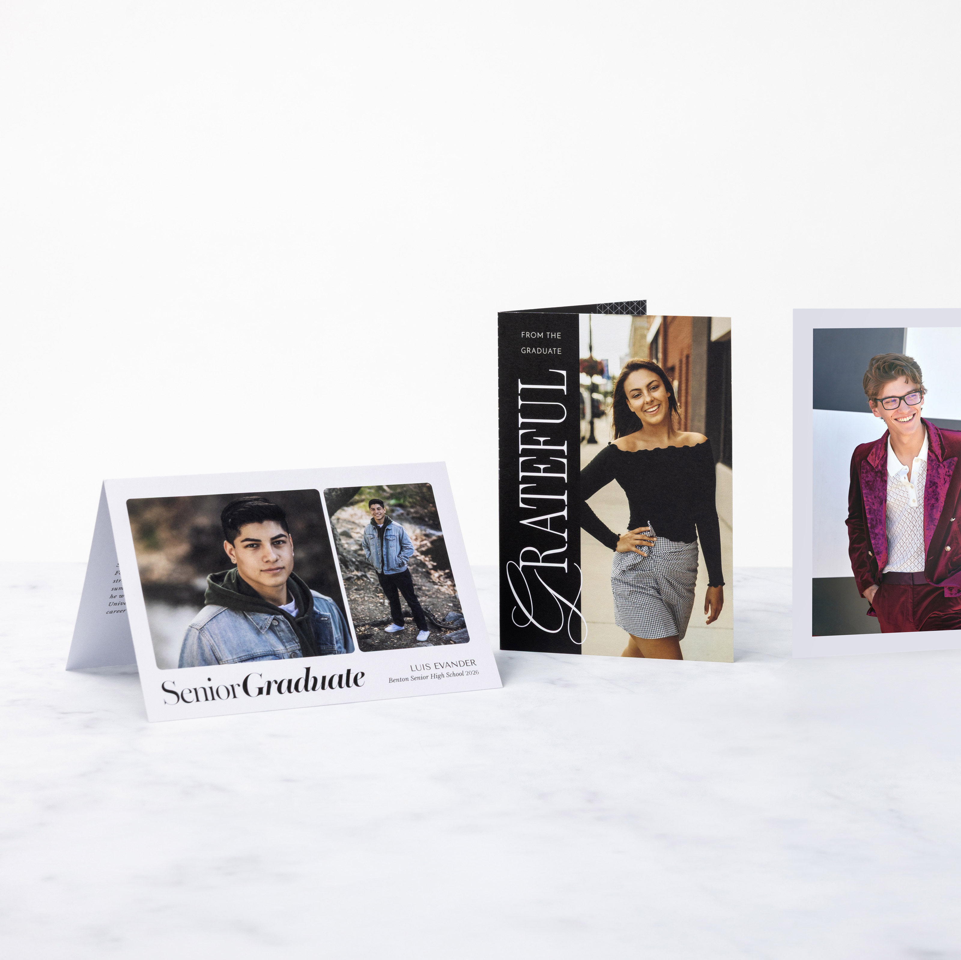 One horizontal and two vertical Folded Cards standing on on a marble background featuring various senior graduation invitation and thank you card designs.
