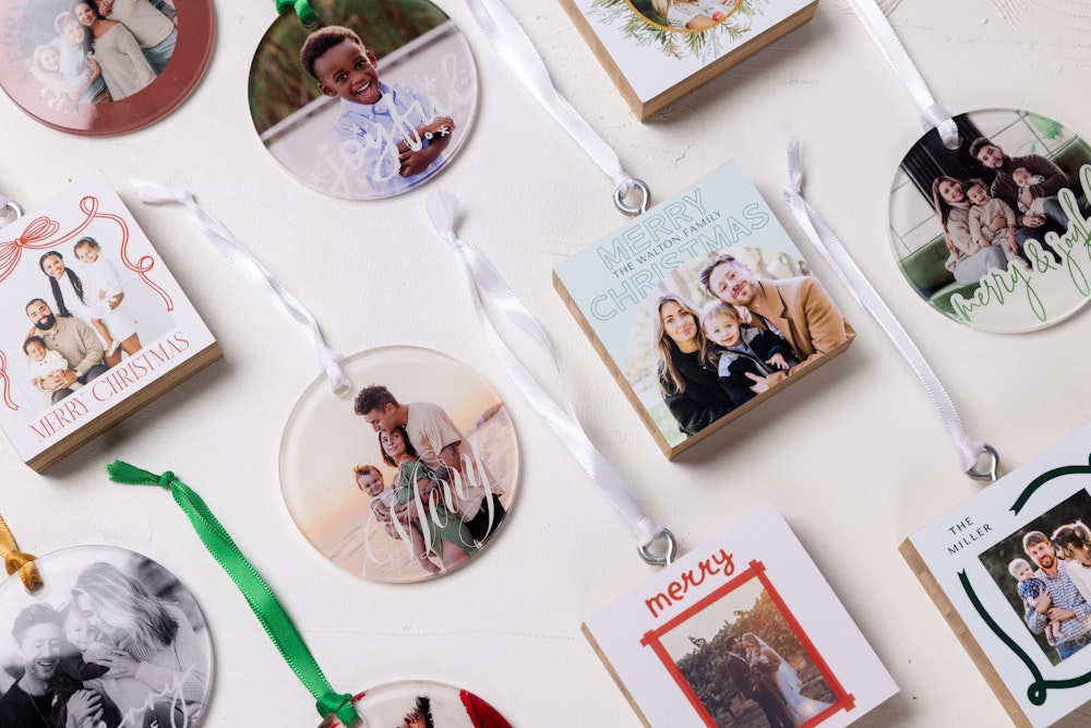 Flatlay of multiple Bamboo and Acrylic Ornaments arranged in an angled grid on a white, textured background. Each custom-printed ornament features professional portrait photography from family sessions and weddings.