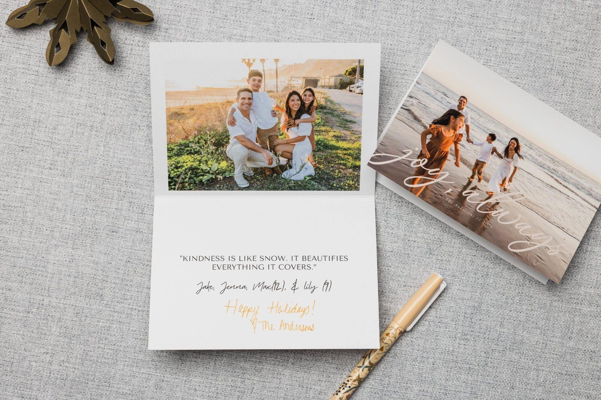 Open folded holiday card with a handwritten message beside a folded card front with a beach family photo