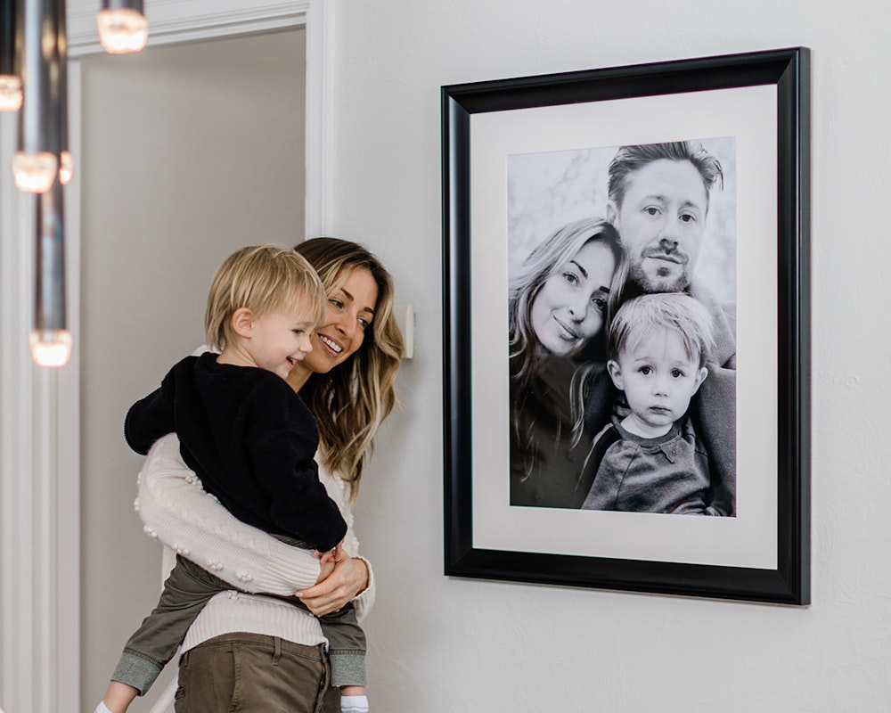 Black framed print styled on a home wall with mom and child