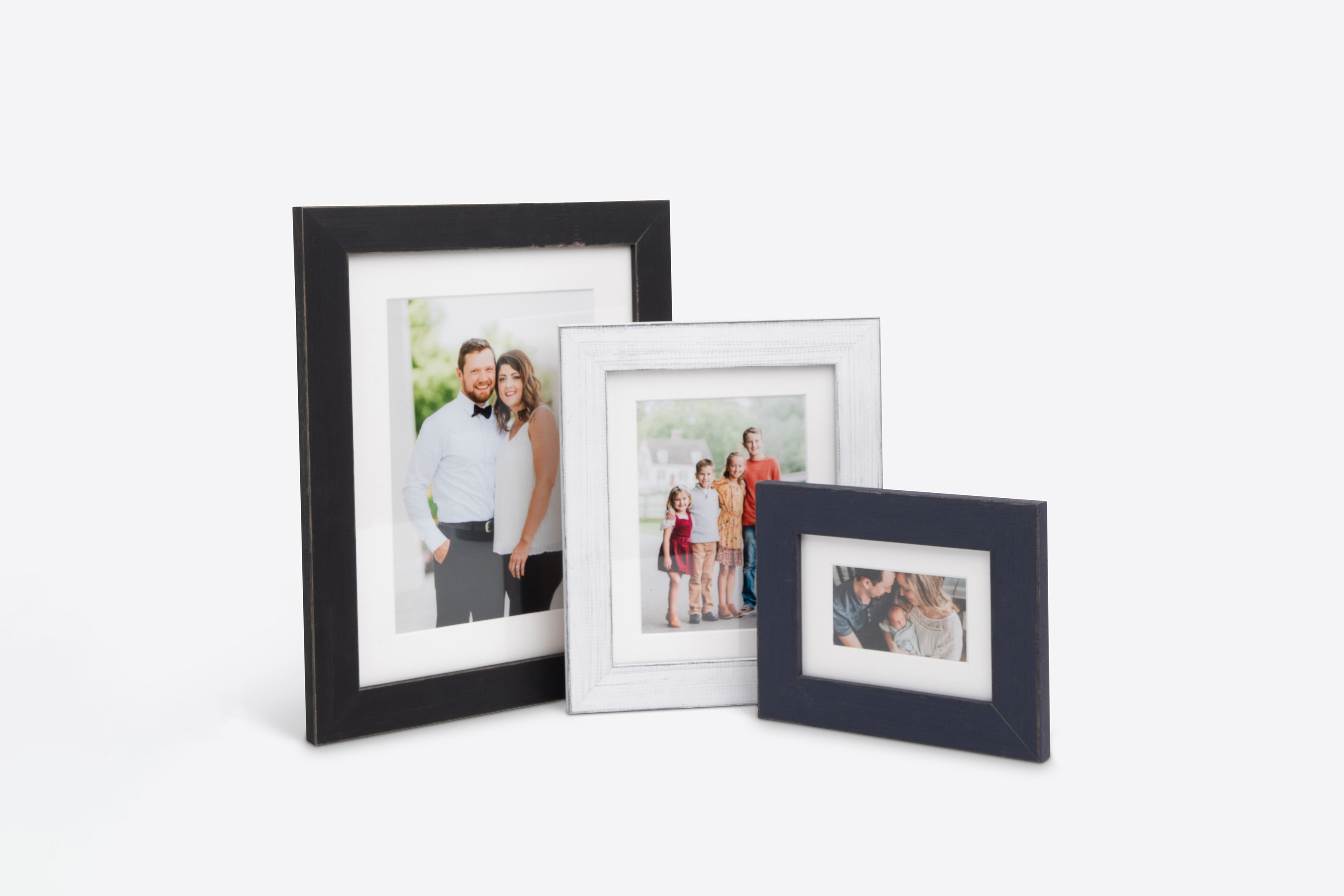 Three Framed Prints of various sizes featuring professional family portrait photography paired with a black, white, and navy Distressed moulding option.