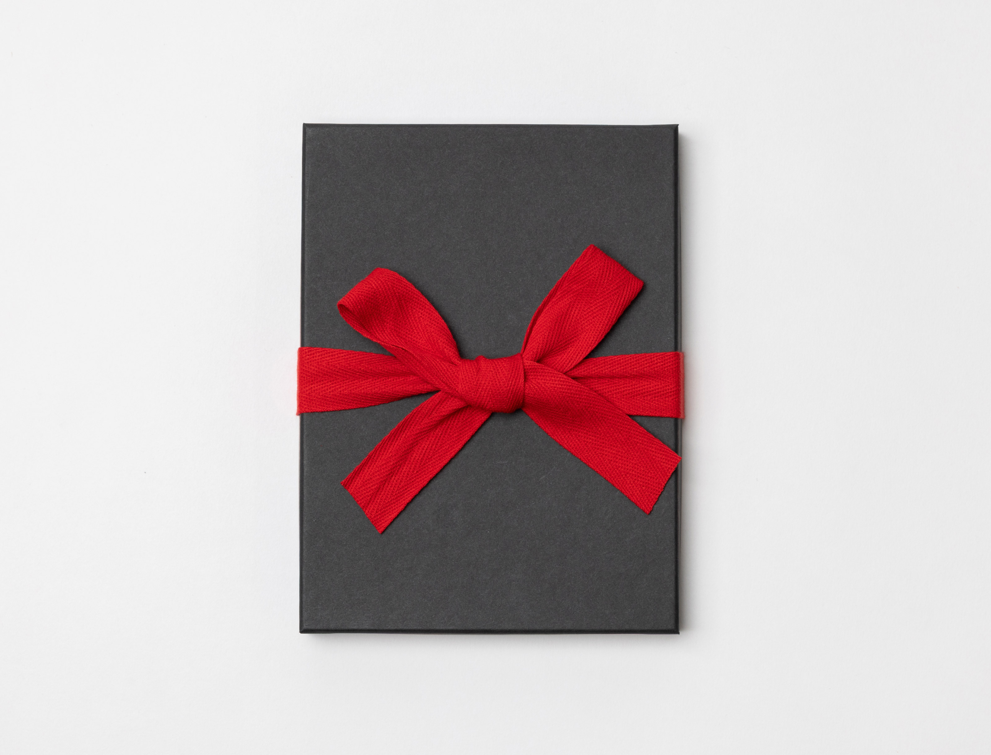 Charcoal Premium Packaging box with a red ribbon tied in a bow on a light gray background