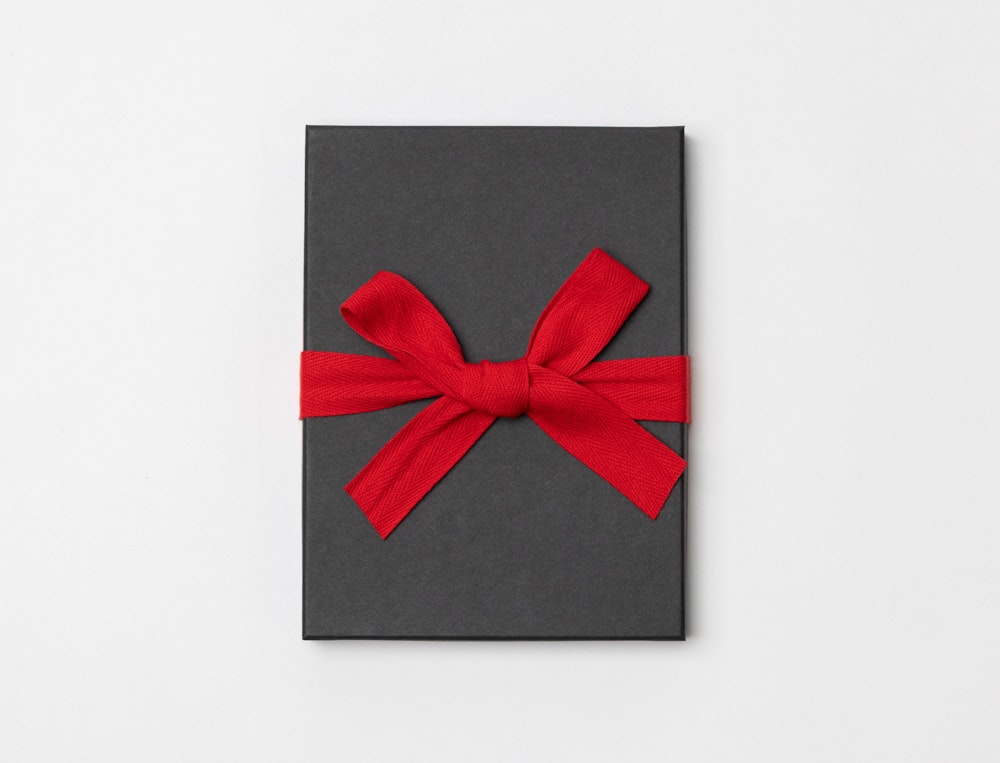 Charcoal Premium Packaging box with a red ribbon tied in a bow on a light gray background