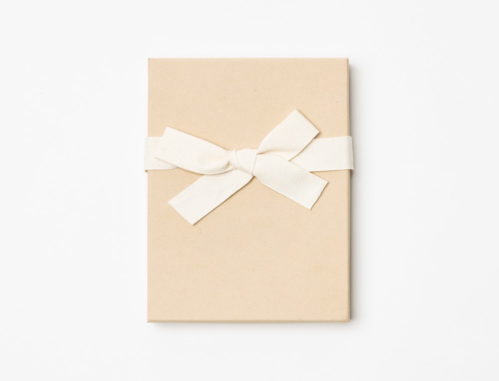 Kraft Premium Packaging box with a cream ribbon tied in a bow on a light gray background